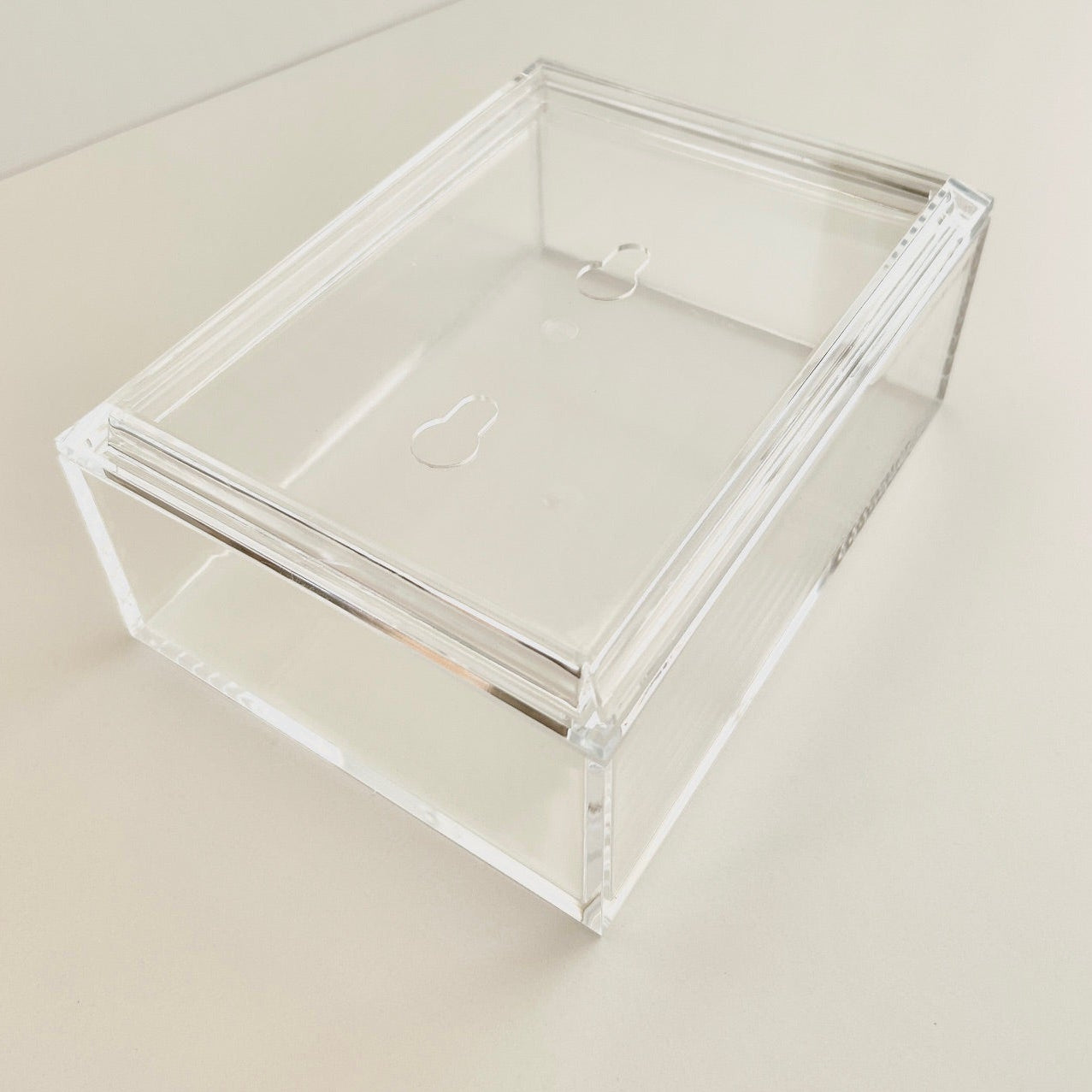 Clear acrylic box on a beige surface with a neutral background