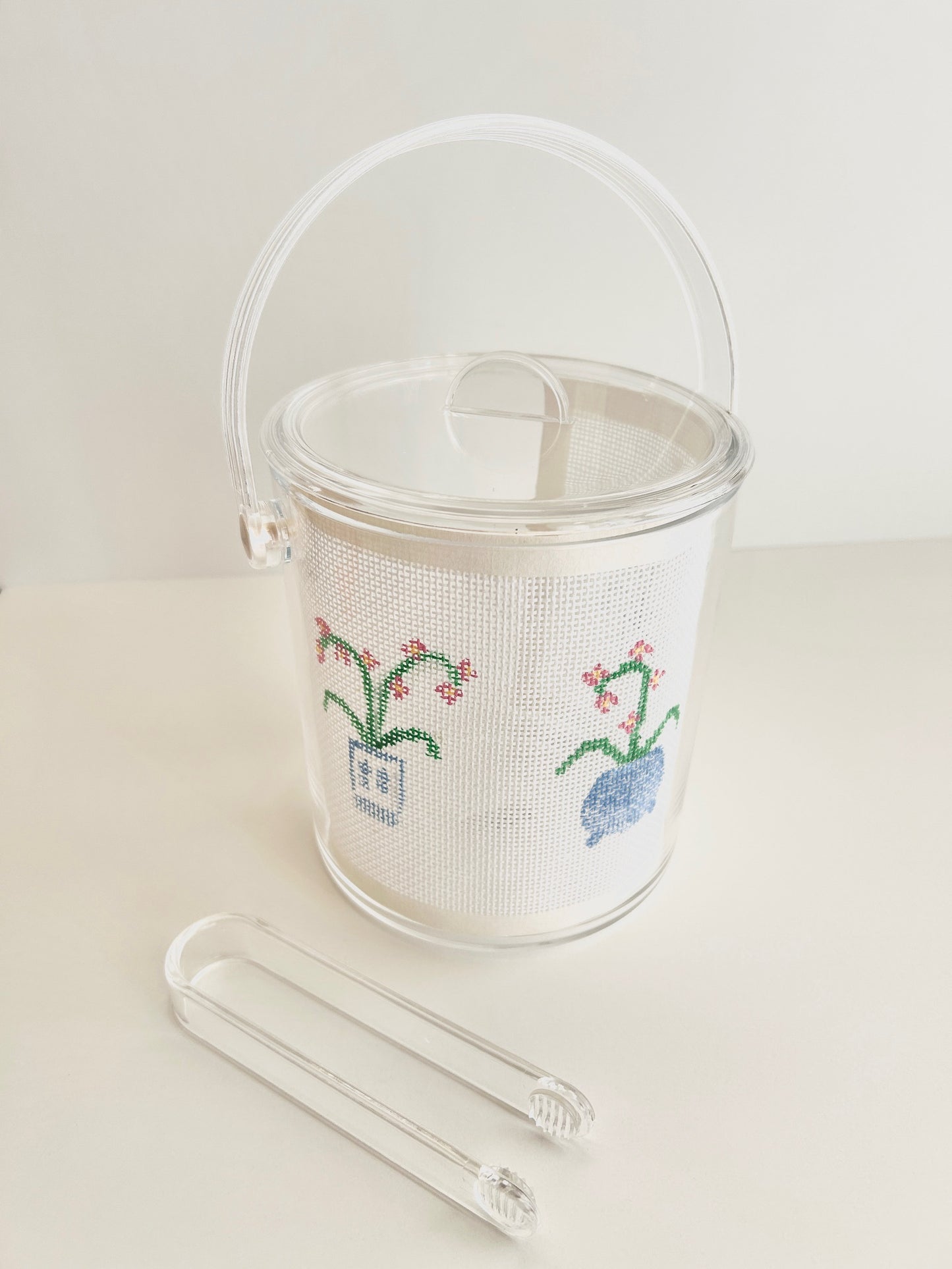Acrylic ice bucket with room for displaying needlepoint and embroidery designs.