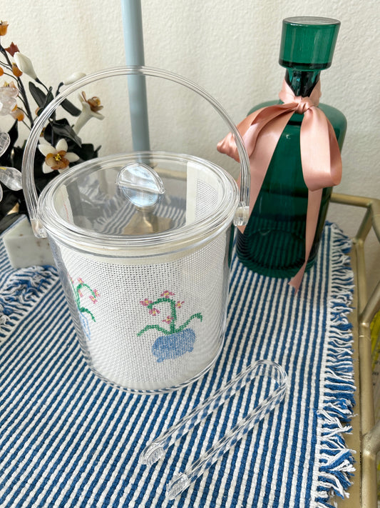 Acrylic ice bucket with a needlepoint design on a bar cart.