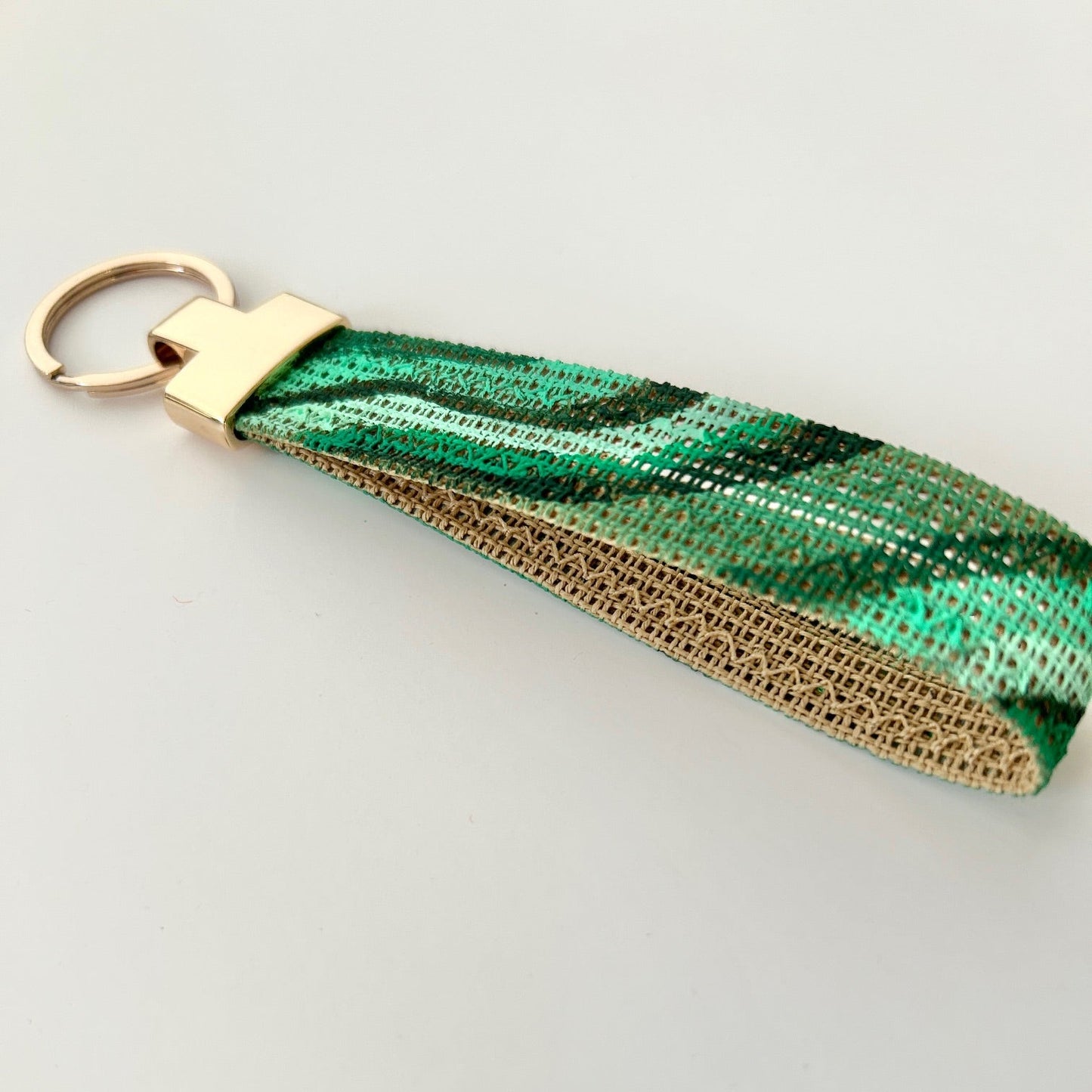 Close up picture of malachite print keychain with gold hardware on a white background
