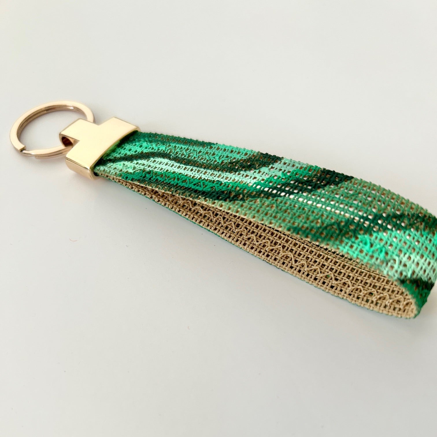 Close up picture of malachite print keychain with gold hardware on a white background