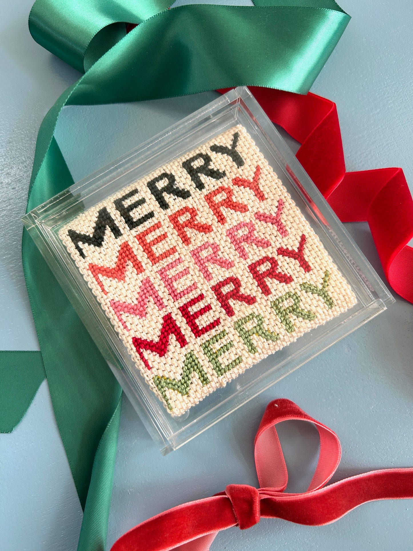 Image of Merry  Merry Needlepoint canvas in an acrylic coaster with holiday ribbons.