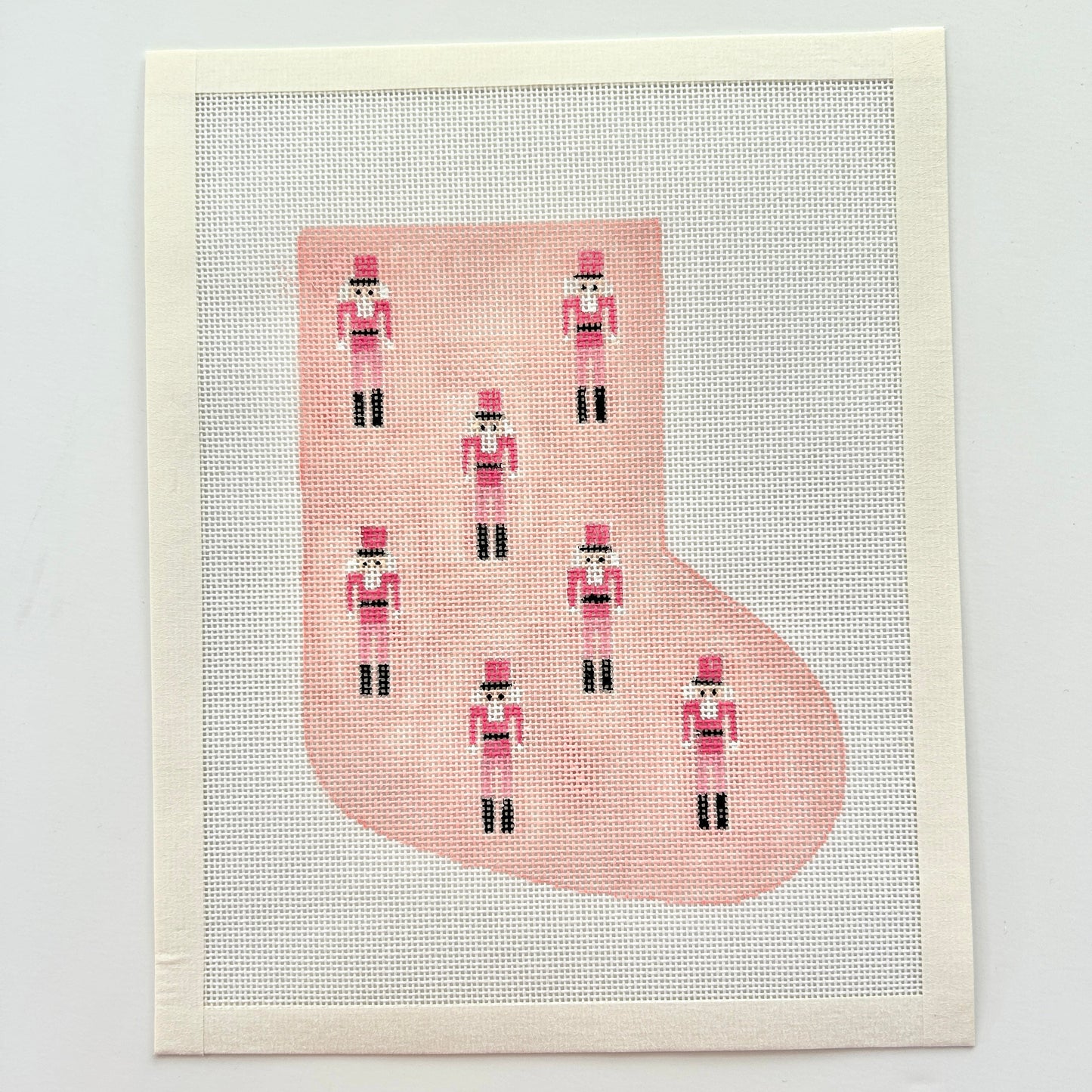 Pink mini nutcracker stocking needlepoint canvas on white background.