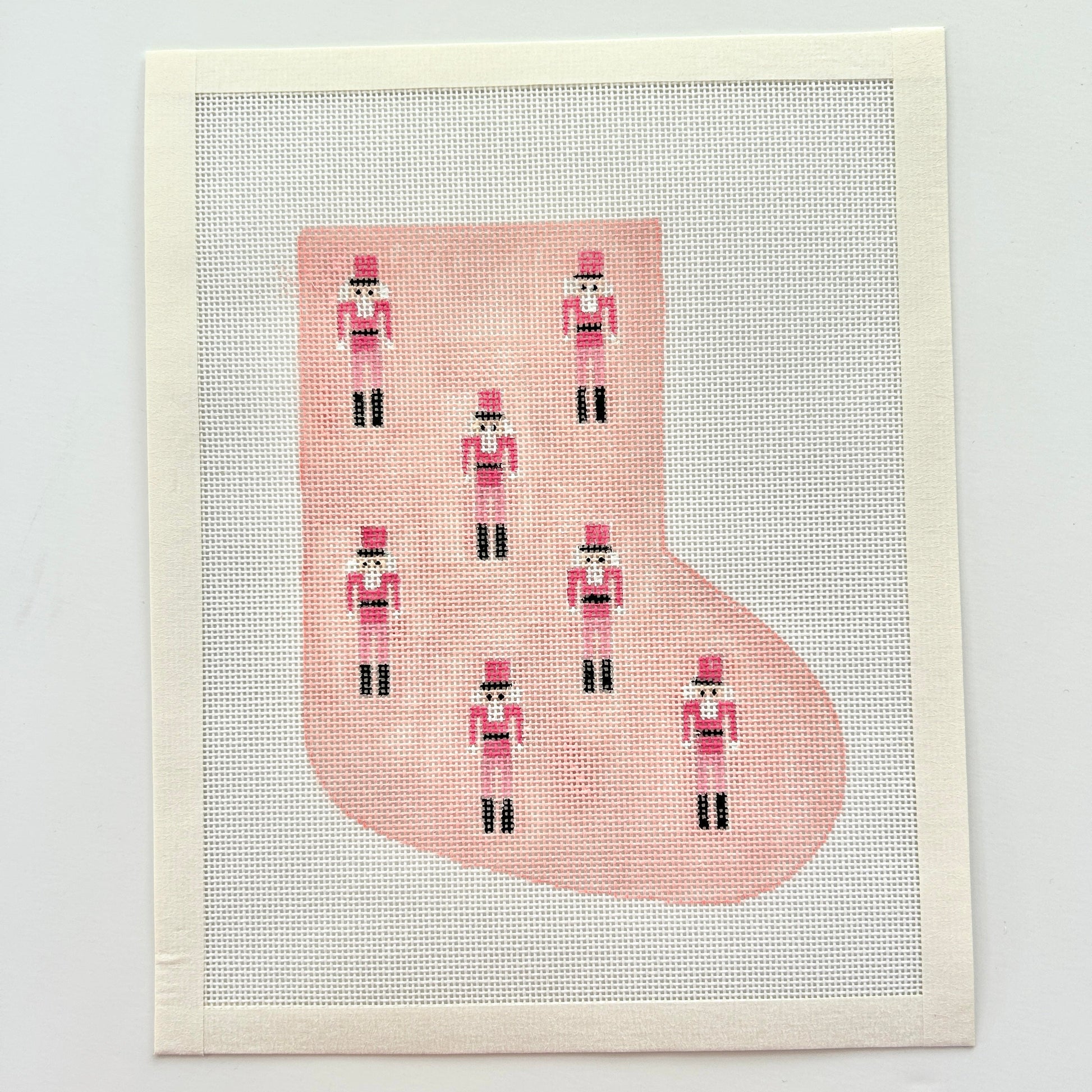 Pink mini nutcracker stocking needlepoint canvas on white background.