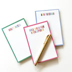 Three colorful Needlepoint notepads on white background with a gold pen.