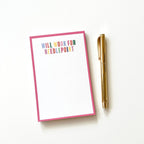 Paper notepad with 'Will work for needlepoint' text and a pen on a white background